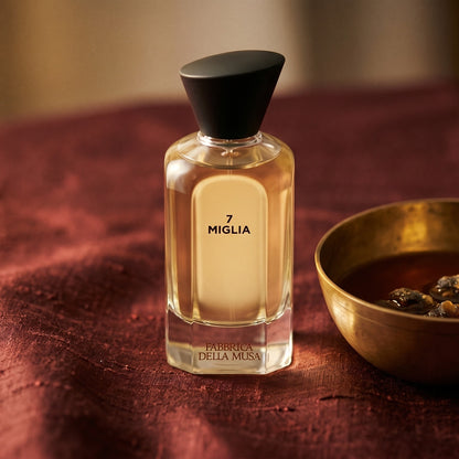 Fabbrica Della Musa Magia Maertrale EDP on raw silk of oxblood color with a brass bowl of ambergris tincture