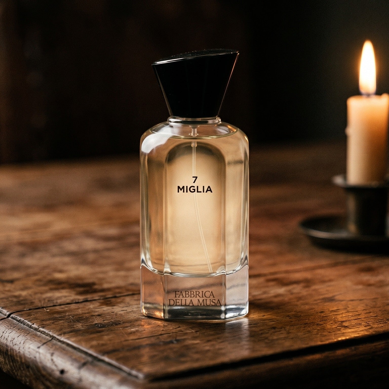 Fabbrica Della Musa Magia Maertrale EDP on rosewood surface with a squat brass candle flickering nearby