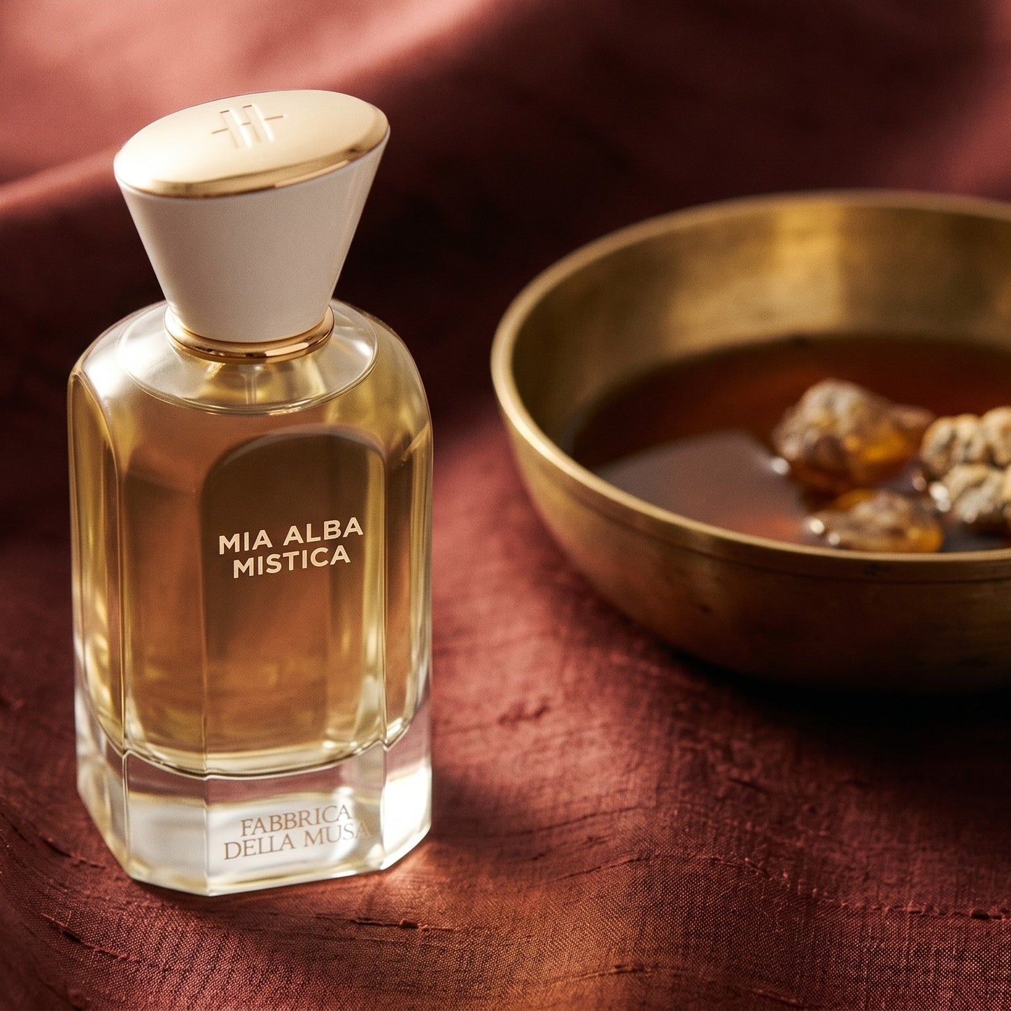 Fabbrica Della Musa Mia Alba Misica EDP on burnt-orange raw silk with a brass vial of frankincense oil