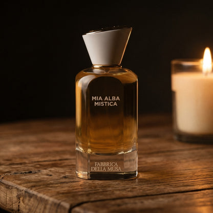 Fabbrica Della Musa Mia Alba Misica EDP on rosewood surface with a squat brass candle flickering nearby