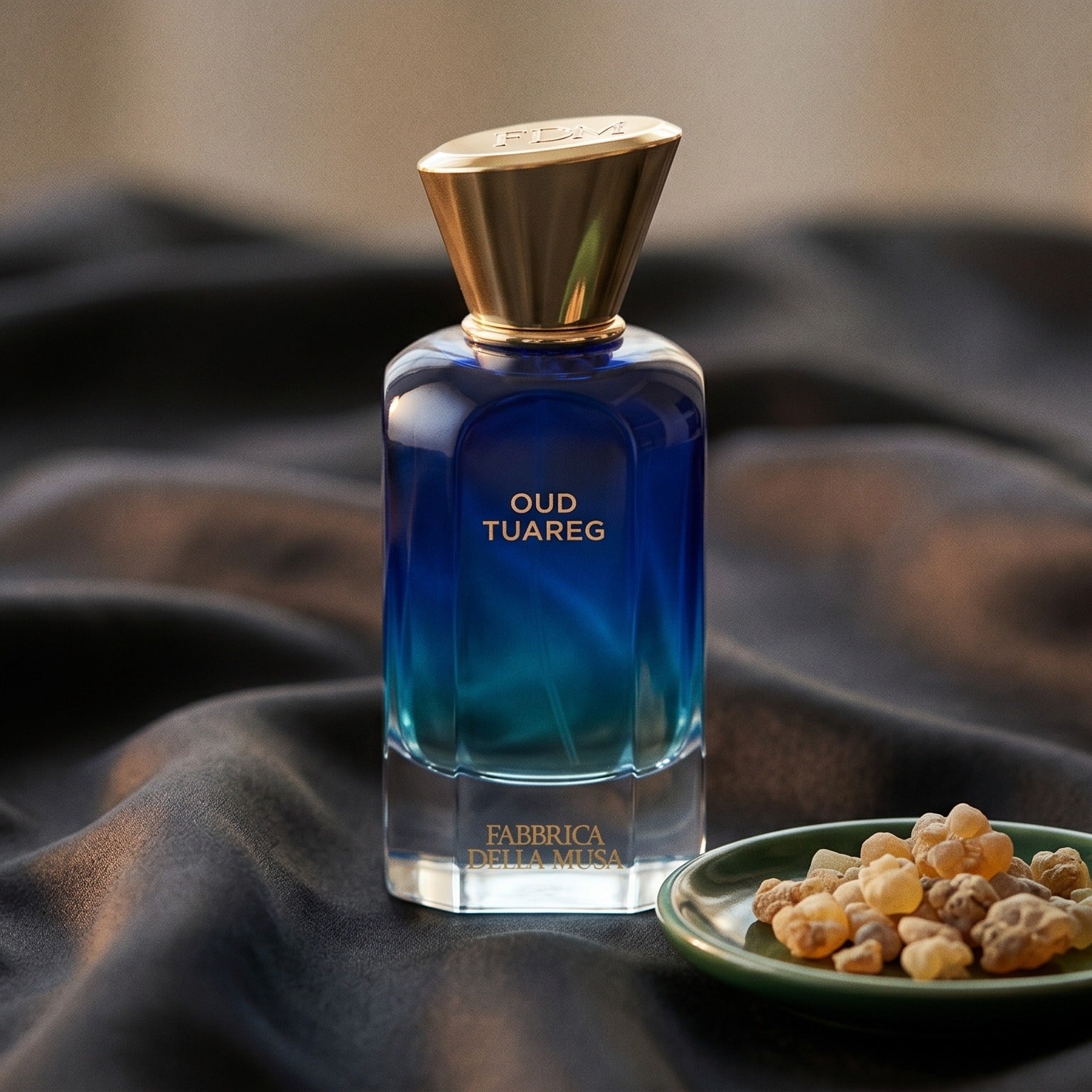 Fabbrica Della Musa Oud Tuareg Extrait de Parfum on charcoal raw silk with amber resin pieces near the bottle base