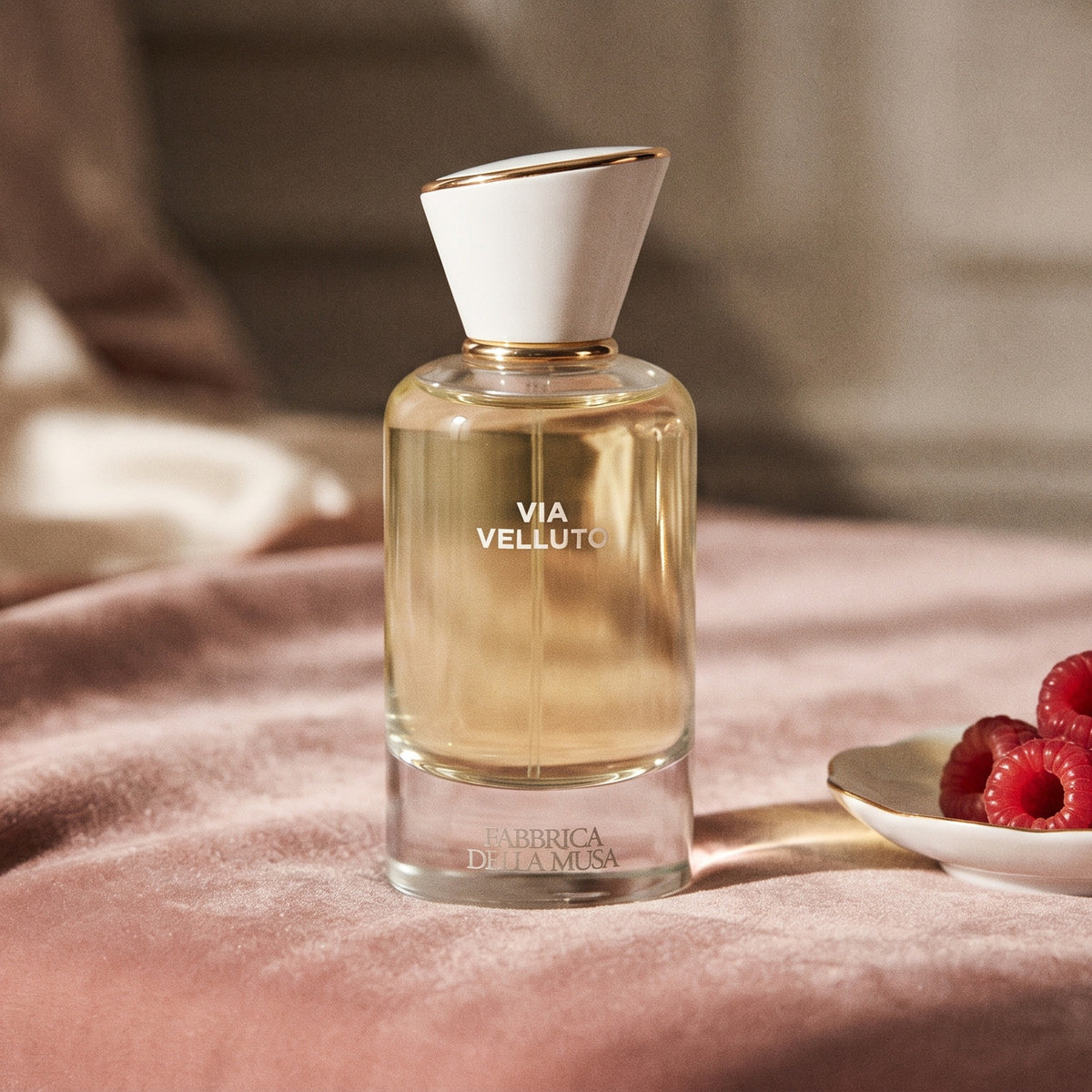 Fabbrica Della Musa Via Velluto EDP on blush pink velvet with fresh raspberries in a porcelain dish