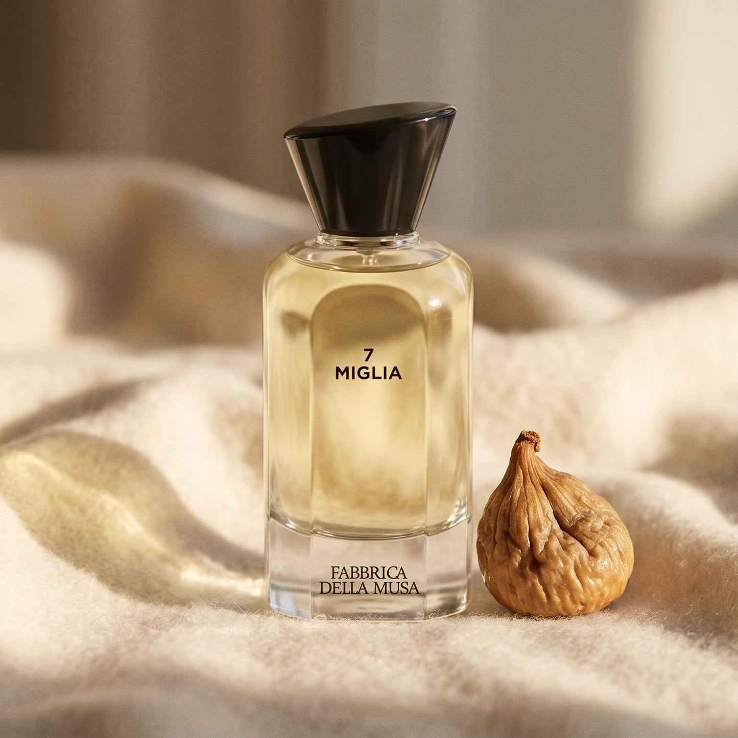 Fabbrica Della Musa Via Velluto EDP on cream cashmere with a single dried fig placed beside the bottle