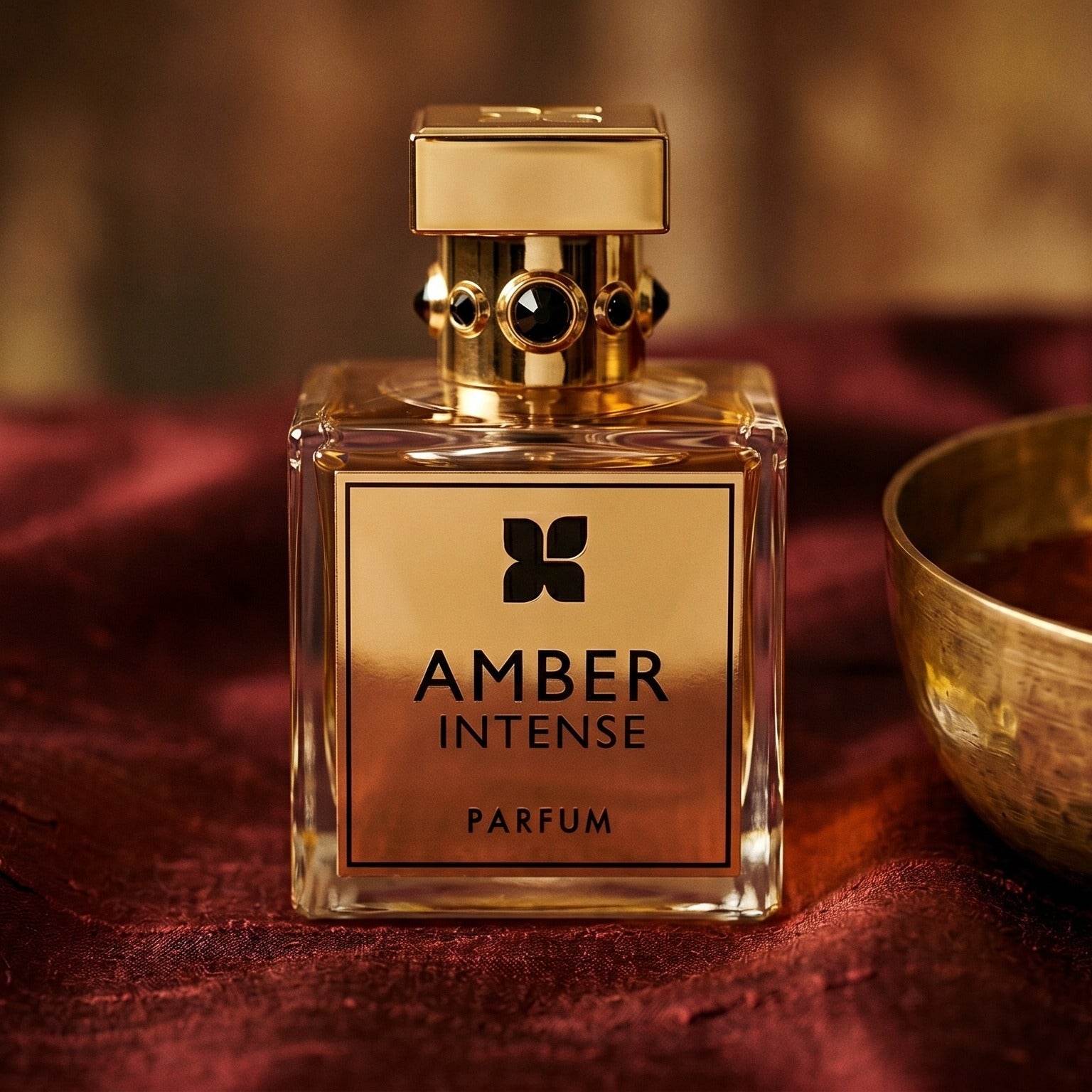 Fragrance du Bois Amber Intense EDP on russet silk with a matte brass bowl holding tonka and amber pieces