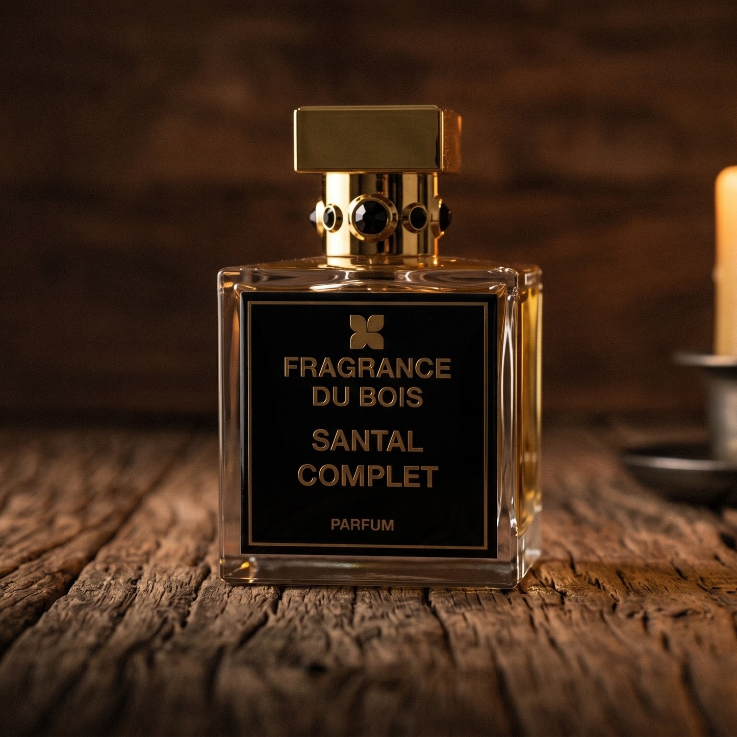 Fragrance du Bois Santal Complet Parfume on reclaimed oak surface with a glass hurricane lamp softly glowing