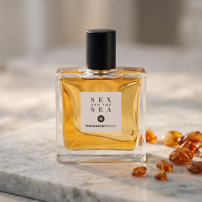 Francesca Bianchi Sex and the Sea EDP on pale grey marble with amber resin beads scattered to one side