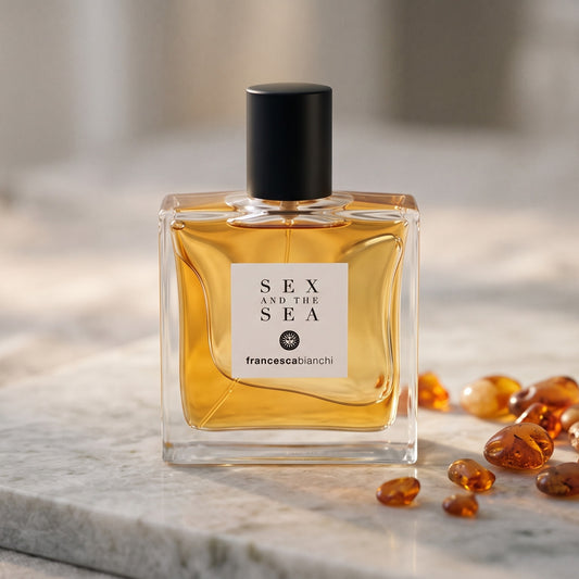 Francesca Bianchi Sex and the Sea EDP on pale grey marble with amber resin beads scattered to one side