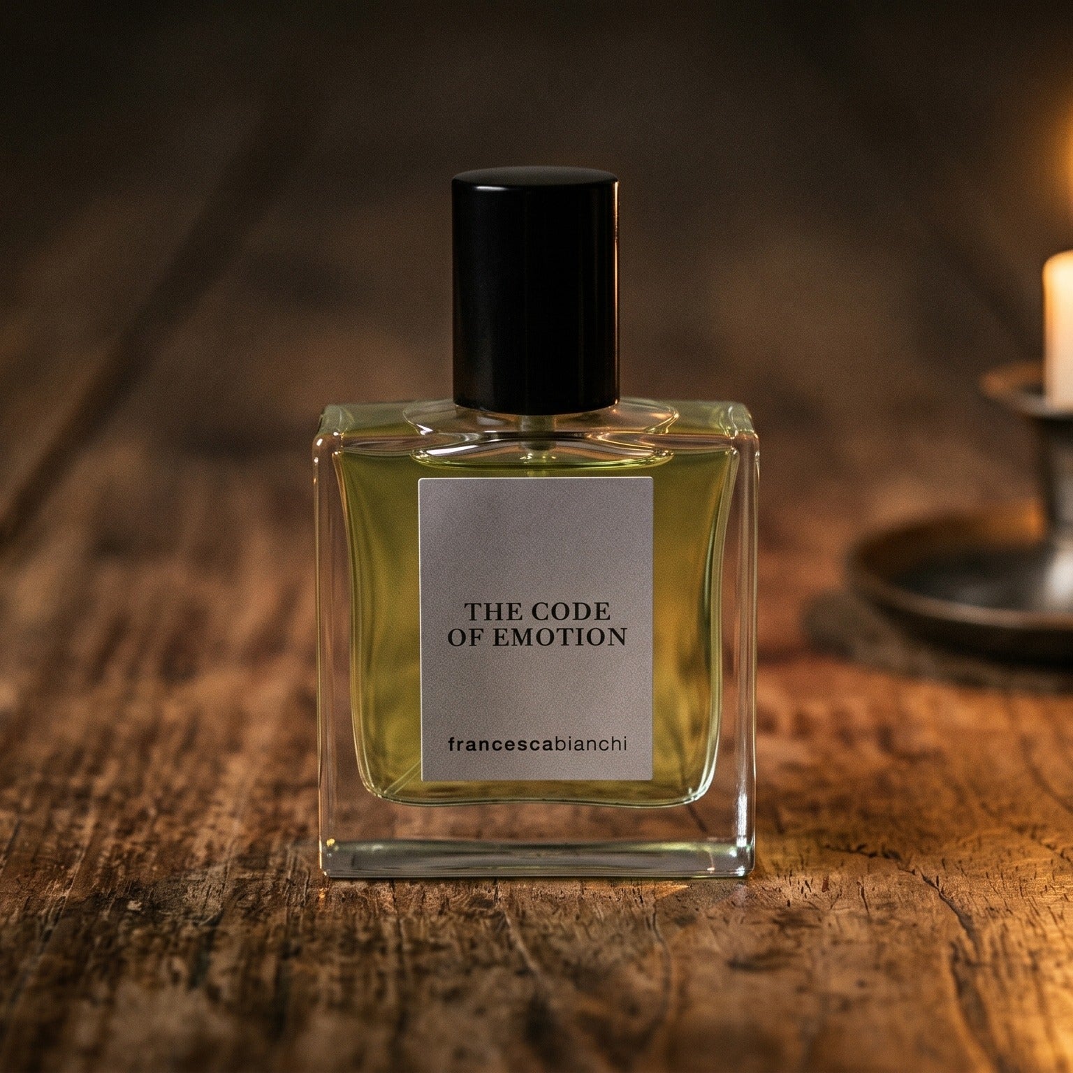 Francesca Bianchi The Code Emotion Extrait de Parfume on reclaimed oak surface with a glass hurricane lamp softly glowing