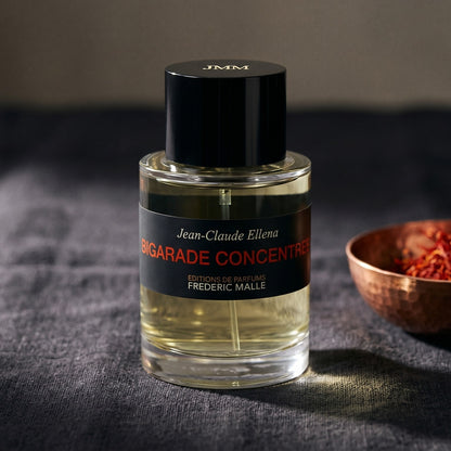 Frederic Malle Bigarade Concentree EDT on slate-grey fabric with a pinch of black peppercorns scattered