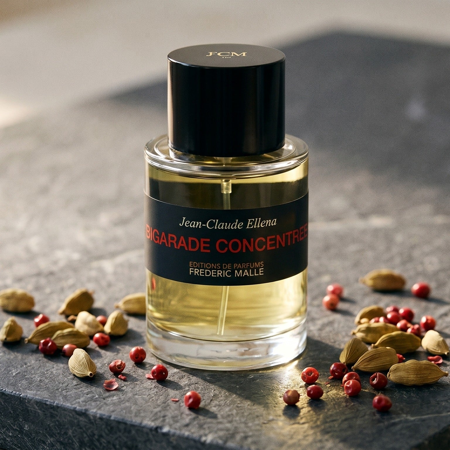 Frederic Malle Bigarade Concentree EDT on charcoal-toned marble with ground turmeric in a brass spoon