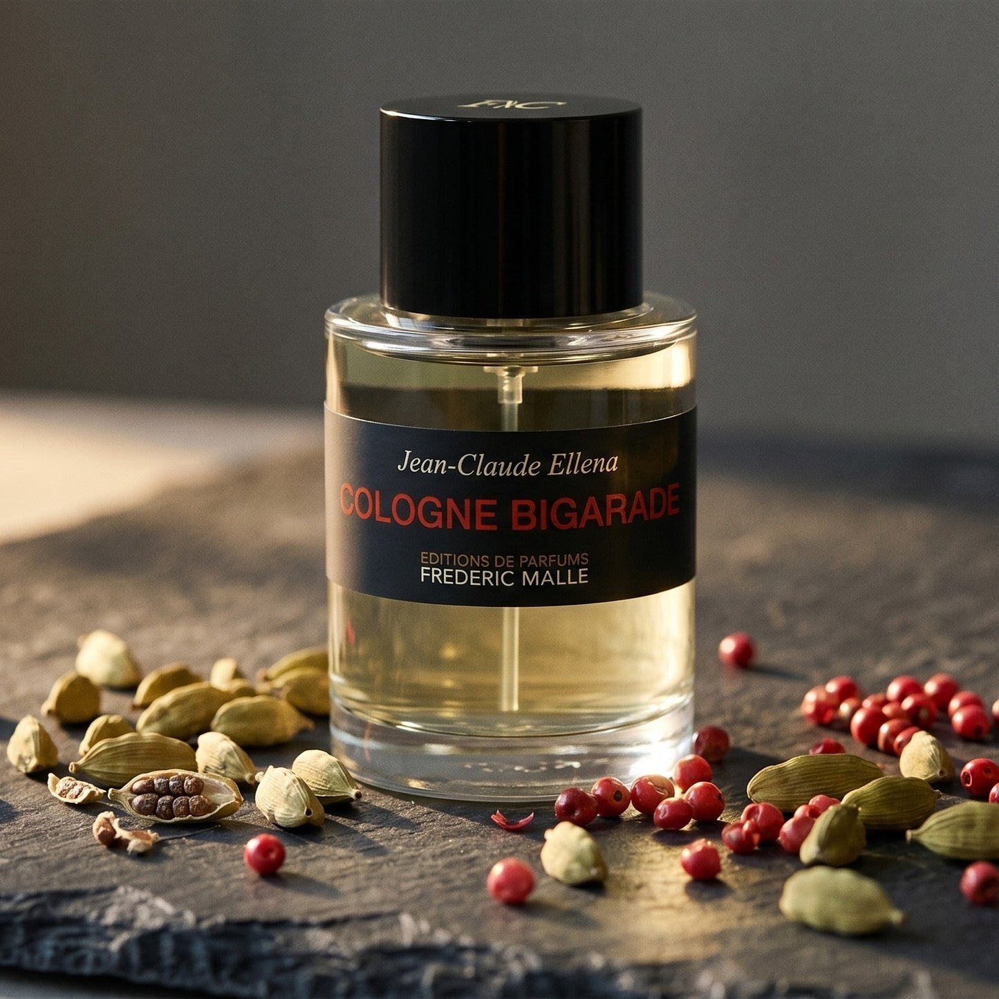 Frederic Malle Cologne Bigarade EDC on slate surface with a handful of dried chili threads near the bottle