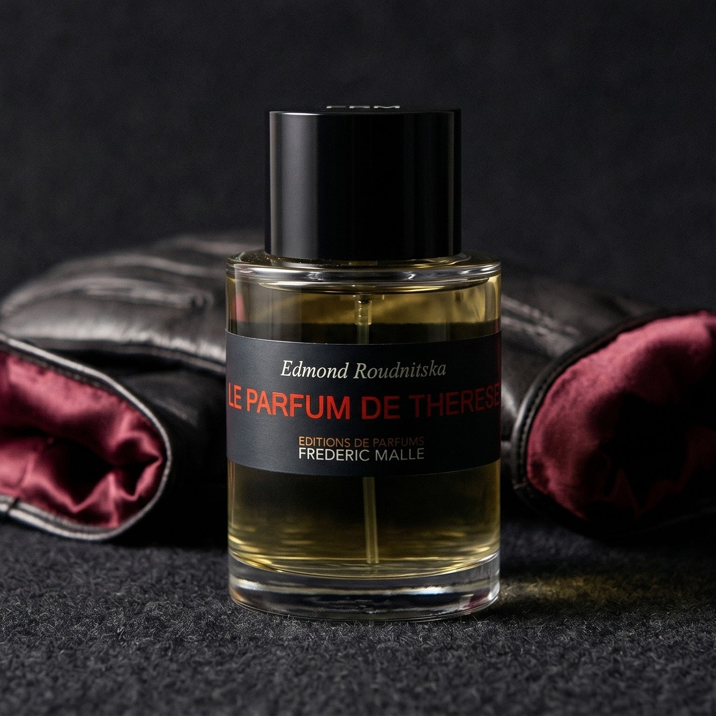 Frederic Malle Le Parfum De Therese EDP on dark grey baize with a braided leather bracelet coiled loosely