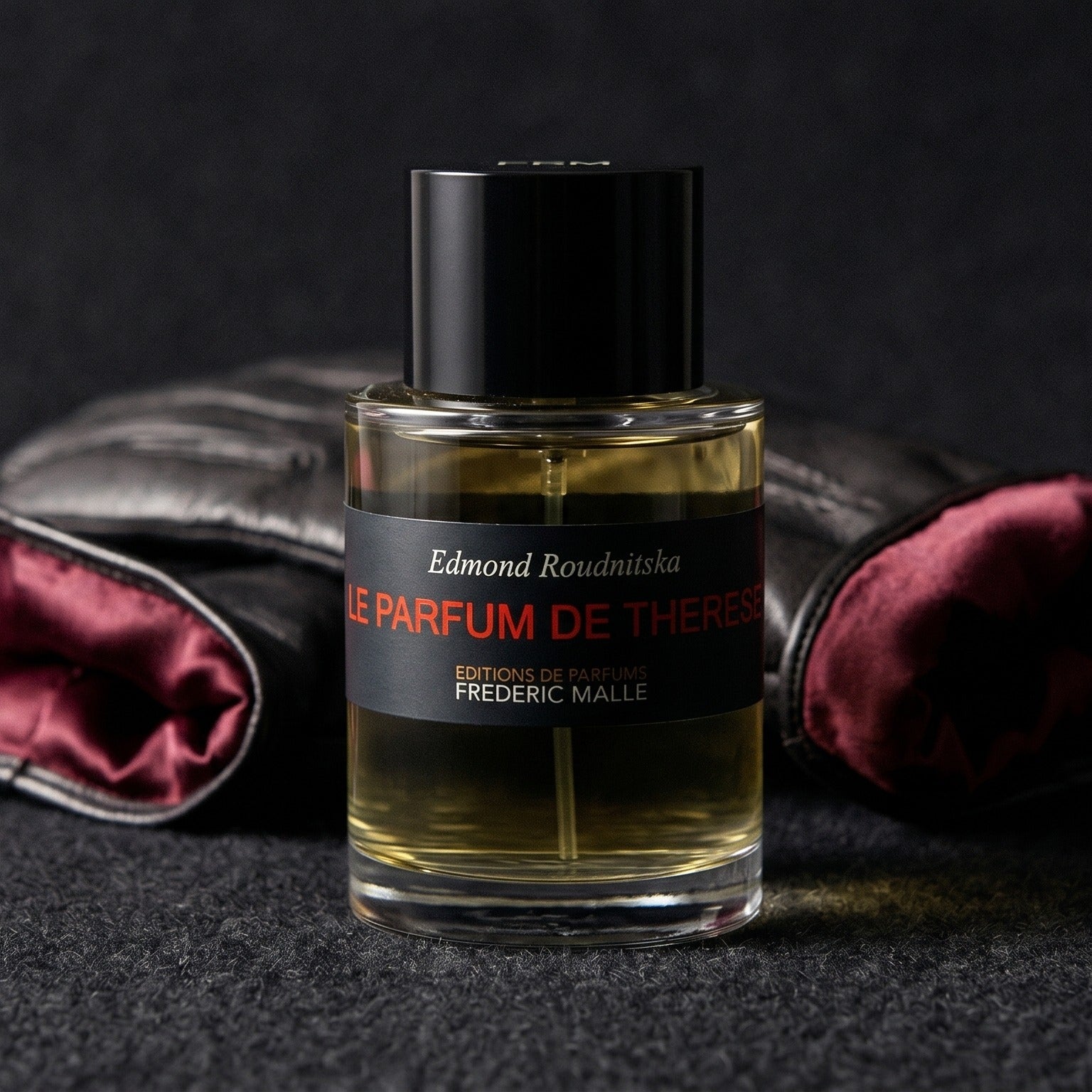 Frederic Malle Le Parfum De Therese EDP on dark grey baize with a braided leather bracelet coiled loosely