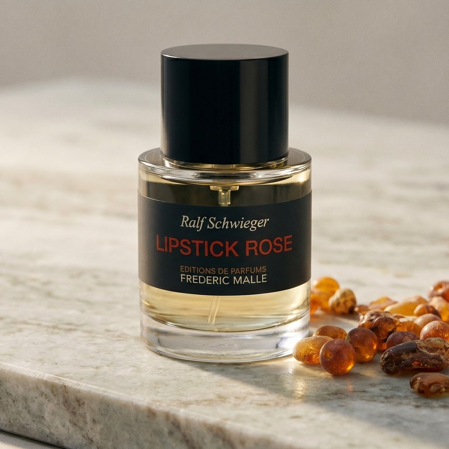 Frederic Malle Lipstick Rose EDP on polished limestone with benzoin resin pebbles arranged loosely