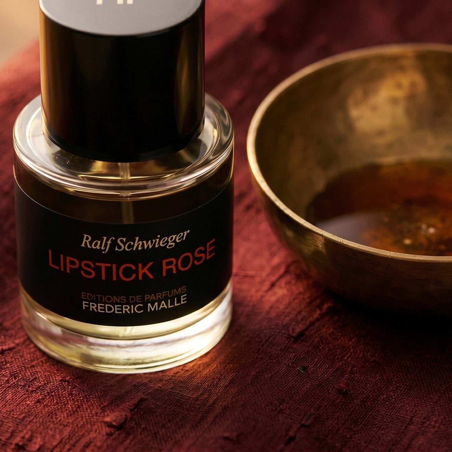 Frederic Malle Lipstick Rose EDP on cinnamon-tone silk with a shallow saucer of warm benzoin resin