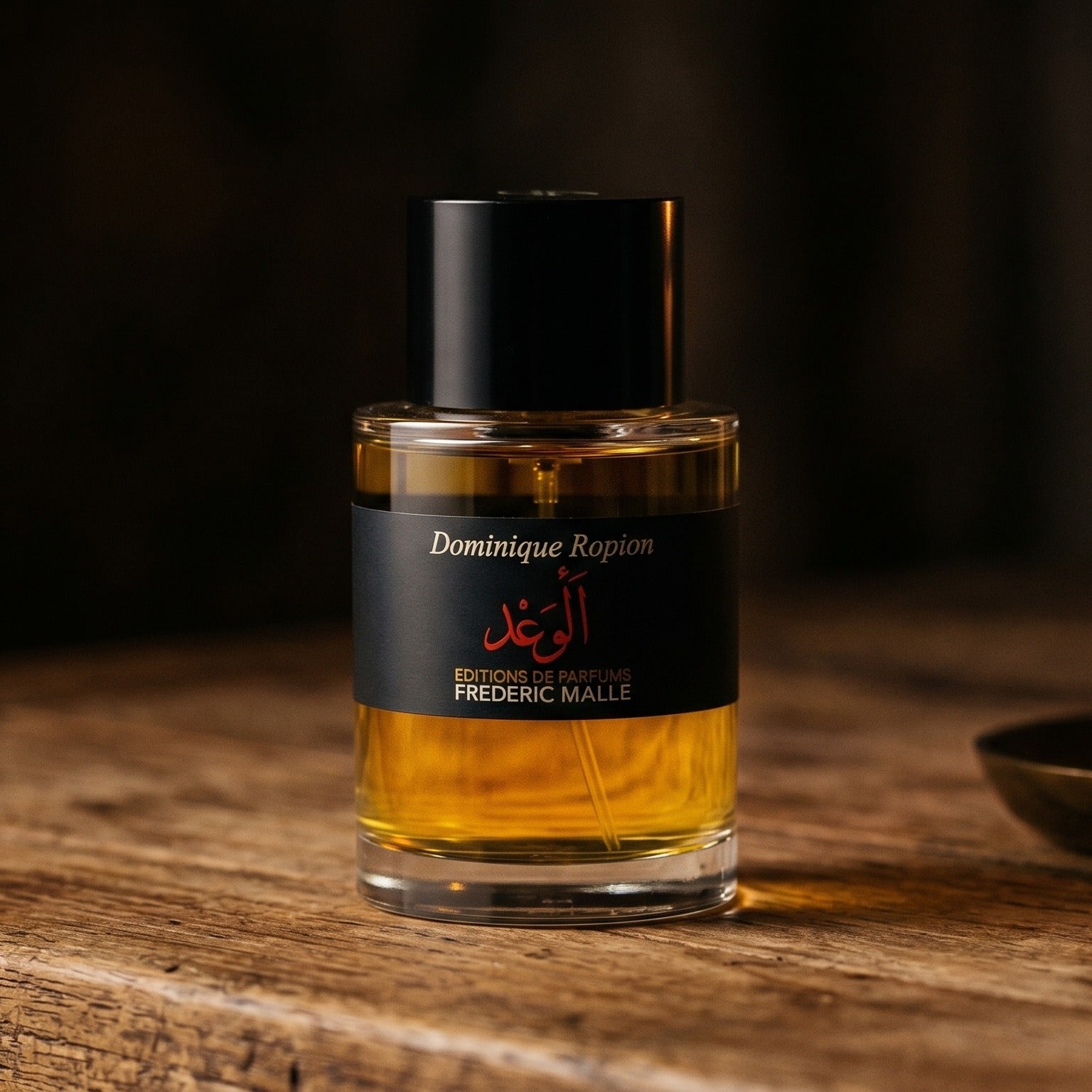 Frederic Malle Promise Parfum on aged teak with a candle burning gently to frame-right