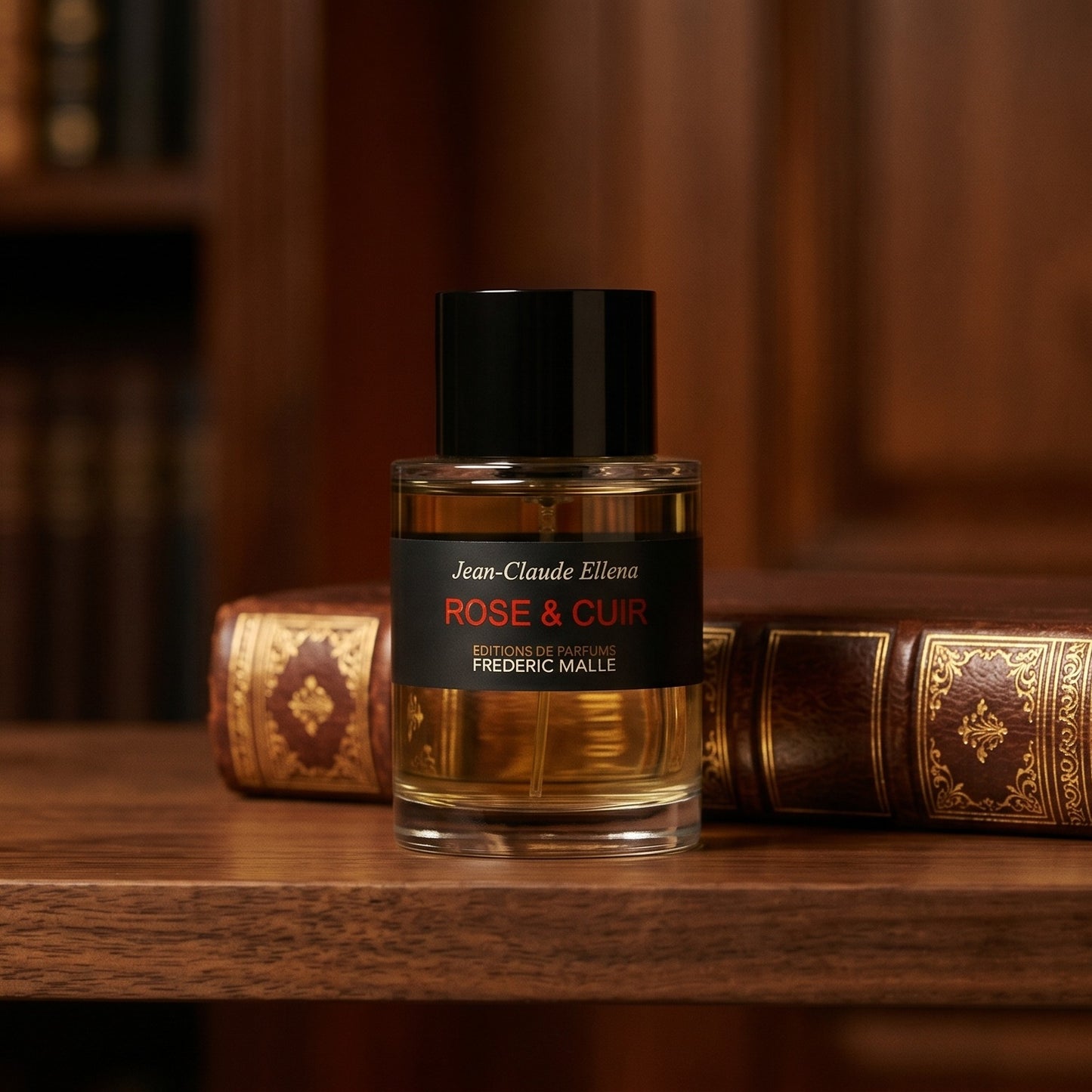 Frederic Malle Rose & Cuir EDP on dark walnut library shelf with a leather-bound book trimmed in gold foil