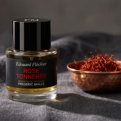 Frederic Malle Rose Tonnere EDP on deep brown linen with a shallow dish of cardamom seeds