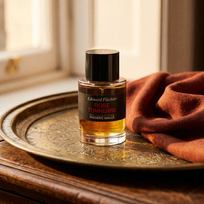 Frederic Malle Rose Tonnere EDP on brass-edged surface with a silk-wool wrap in burnt sienna