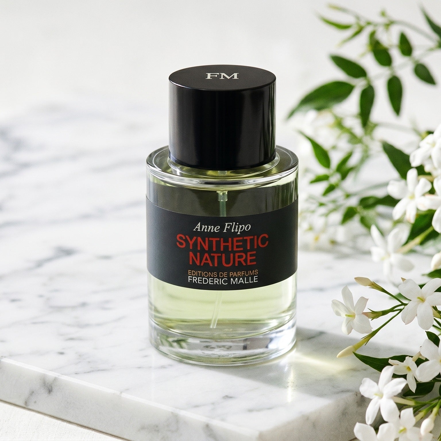 Frederic Malle Synthetic Nature EDP on cream marble with a small bunch of gardenia blooms