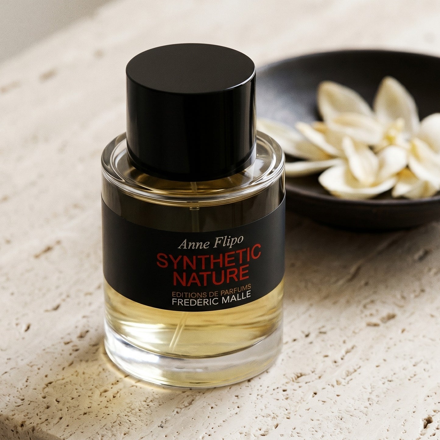 Frederic Malle Synthetic Nature EDP on cream ceramic with ylang-ylang petals drifting from a small dish