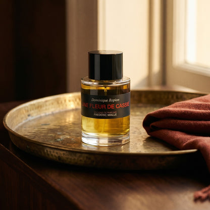 Frederic Malle Une Fleur De Cassie EDP on patinated bronze tray with a folded shawl in deep saffron