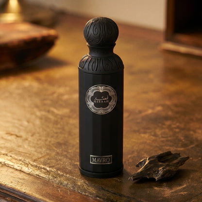 Gissah Mavro EDP on dark tan leather desk with a brass lamp casting a warm pool of light