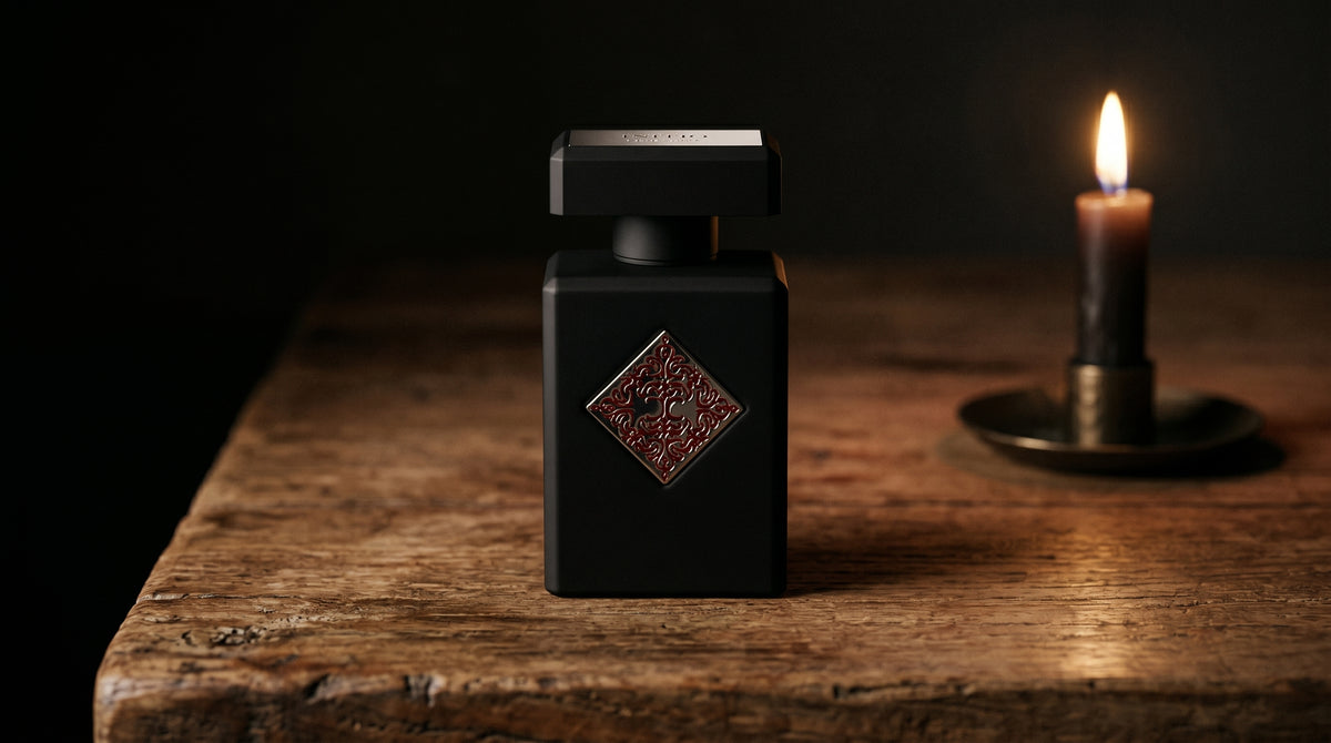 Initio Absolute Aphrodisiac EDP on aged teak with a candle burning gently to frame-right