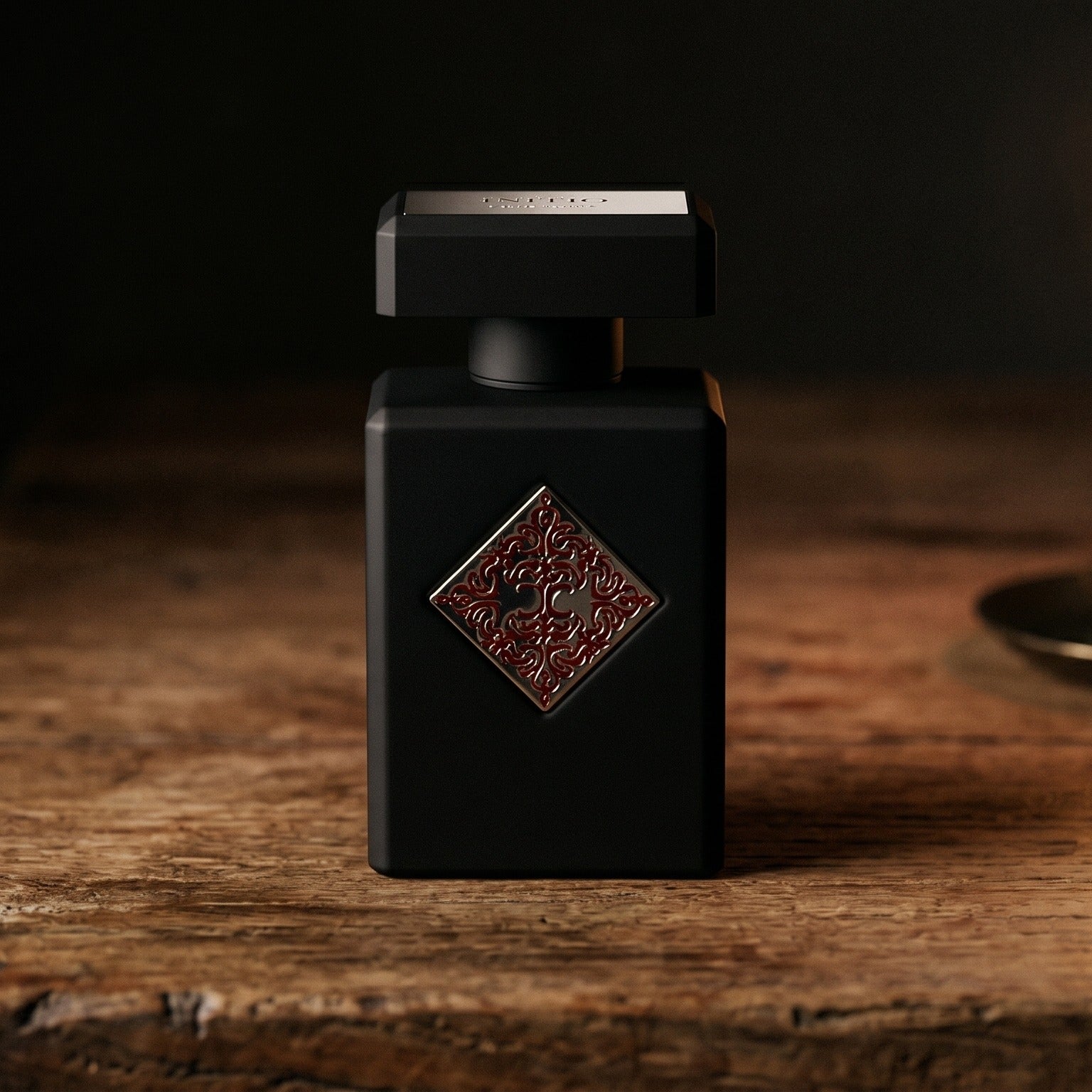 Initio Absolute Aphrodisiac EDP on dark cherrywood with a tall beeswax taper casting warm light