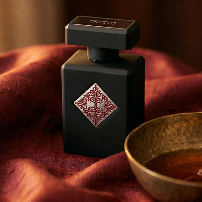 Initio Divine Attraction EDP on deep caramel velvet with a small copper jar of resin balm