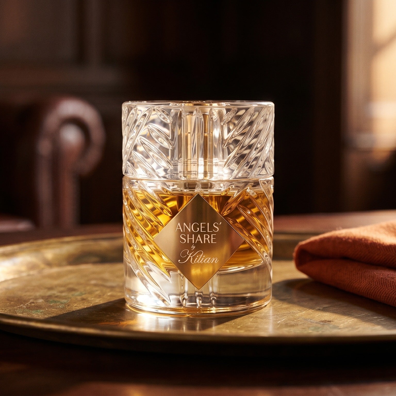 Kilian Angels Share EDP on weathered brass plate with a wool scarf dyed in paprika red
