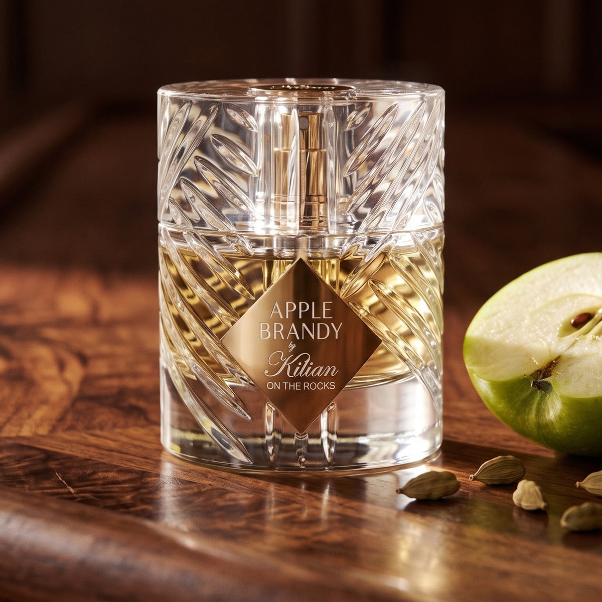 Kilian Apple Brandy on the Rocks on polished walnut bar top with a halved green apple and a few cardamom pods