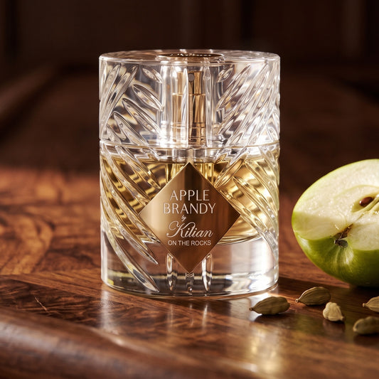 Kilian Apple Brandy on the Rocks on polished walnut bar top with a halved green apple and a few cardamom pods