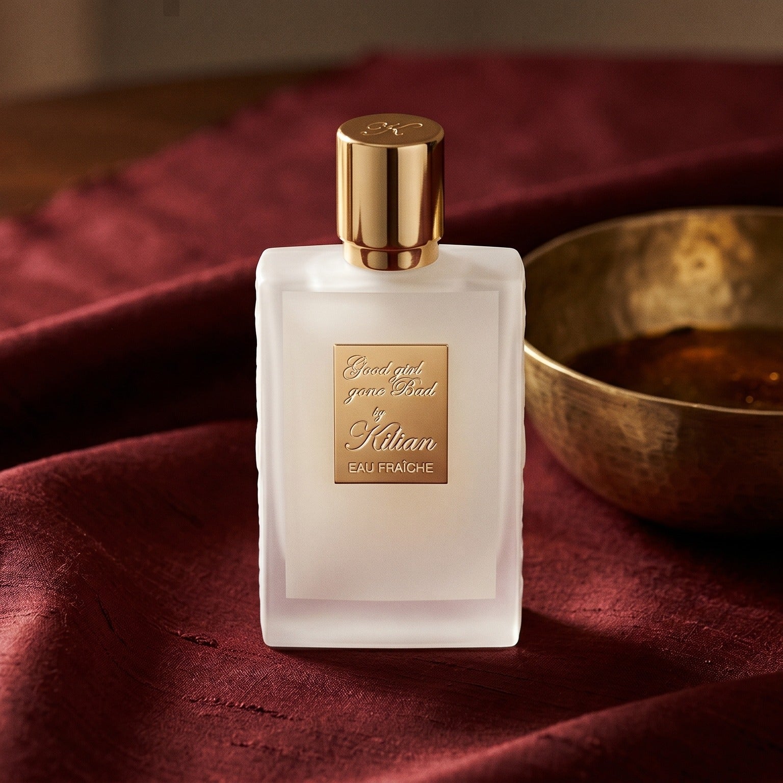 Kilian Good Girl Gone Bad EDP on deep caramel velvet with a small copper jar of resin balm