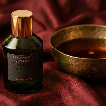Laboratorio Olfattivo Mandarino on amber-toned satin with a gold-rim ceramic dish of labdanum