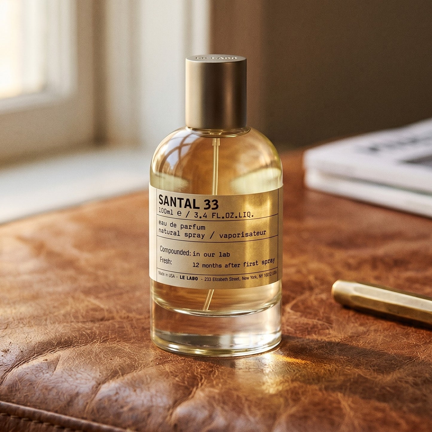 Le Labo Santal 33 on aged cognac-leather surface with a brass fountain pen resting beside the bottle