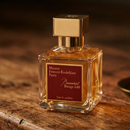 Maison Francis Kurkdjian (MFK) Baccarat Rouge 540 on aged maple with a slender candlestick and drifting smoke