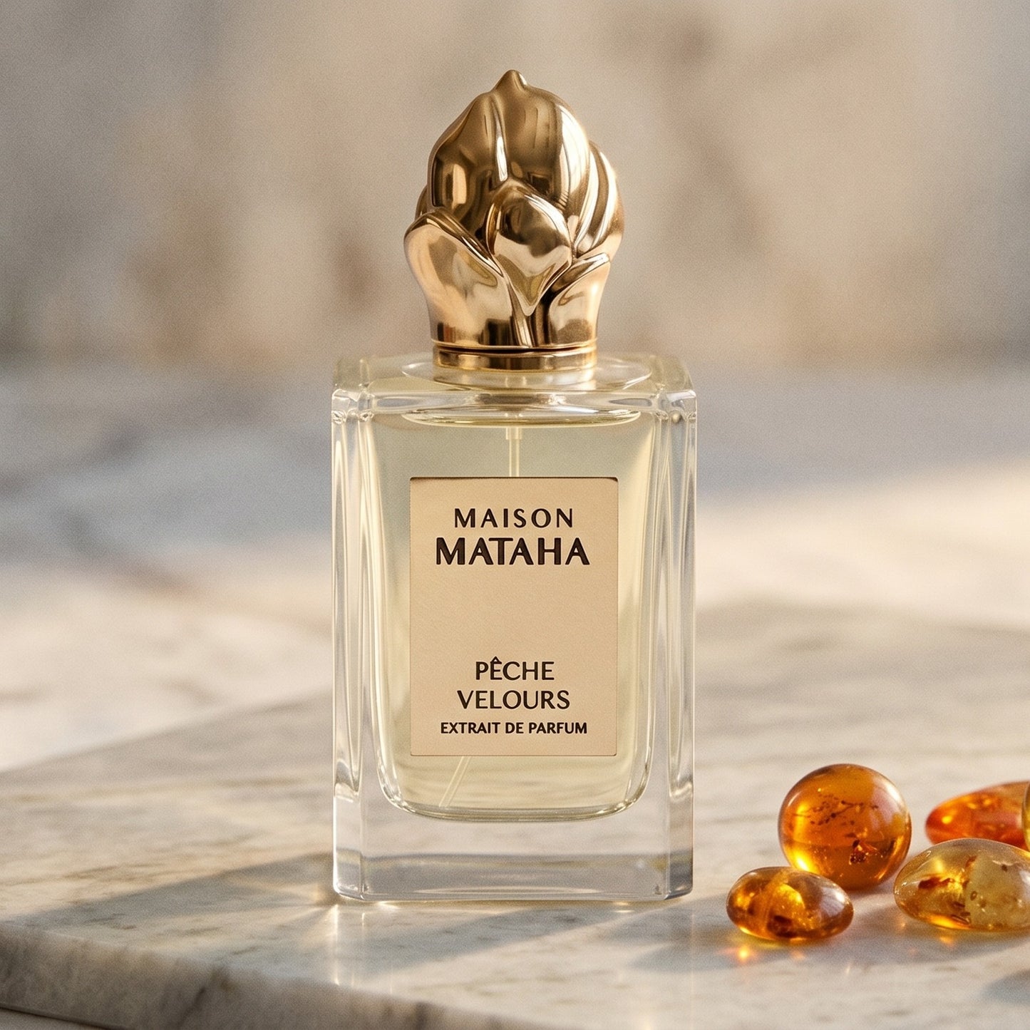 Maison Mataha Peche Velours on cream stone with a scatter of honey-colored ambergris flakes