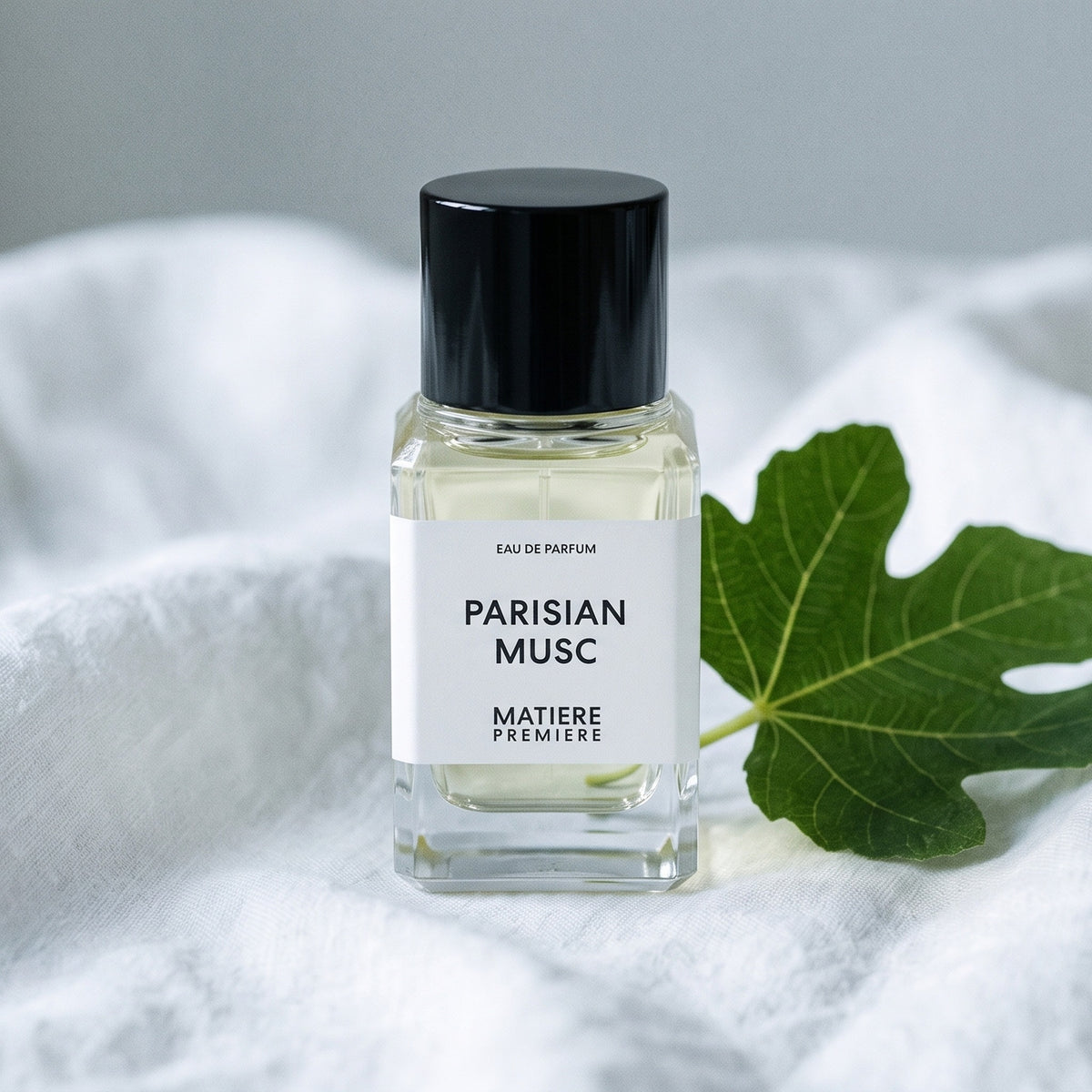 Matiere Premiere Parisian Musc EDP on white linen with a single fresh fig leaf