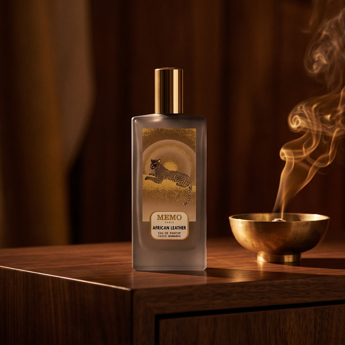 Memo Paris African Leather EDP on dark walnut console with a small brass incense bowl with smoke curling upward