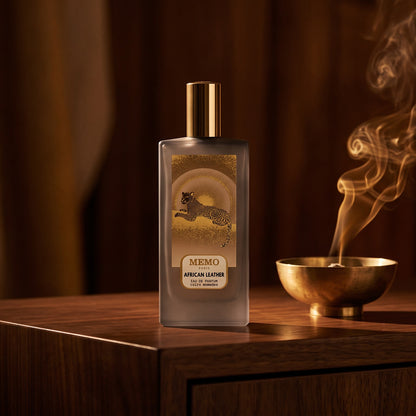 Memo Paris African Leather EDP on dark walnut console with a small brass incense bowl with smoke curling upward
