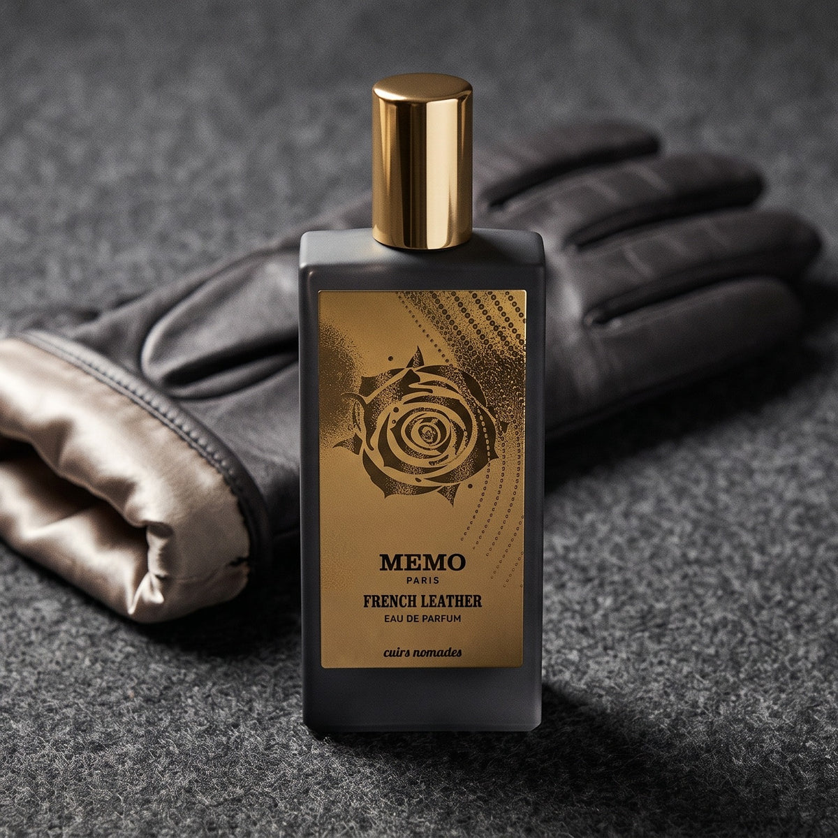 Memo Paris French Leather EDP on charcoal felt with a silk-lined glove just behind the bottle