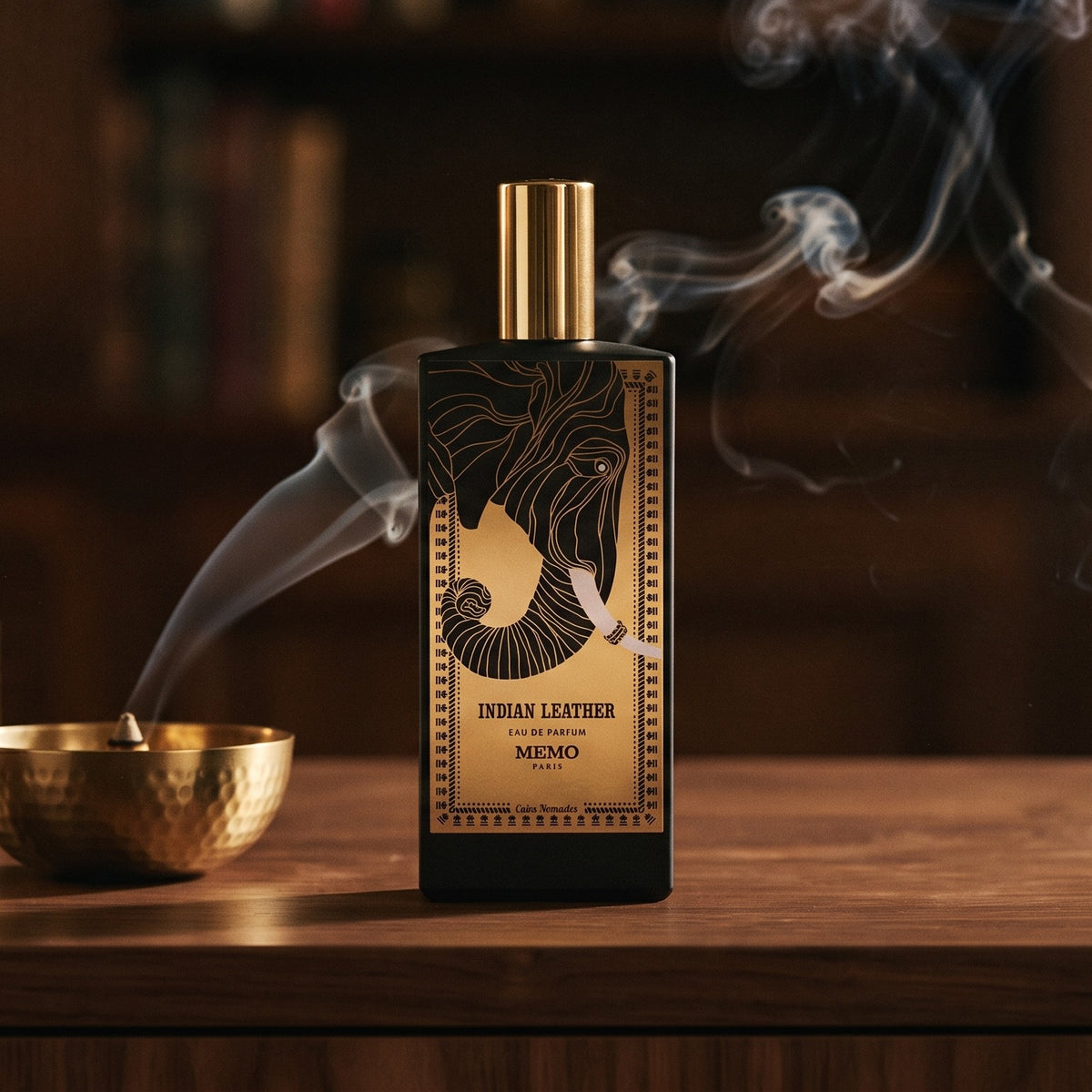 Memo Paris Indian Leather EDP on dark walnut console with a small brass incense bowl with smoke curling upward
