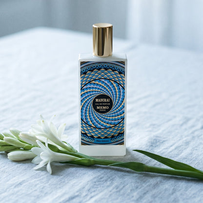 Memo Paris Madurai EDP on bleached linen with a single tuberose stem laid flat