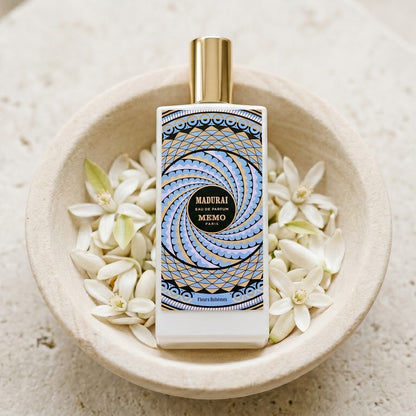 Memo Paris Madurai EDP on pale stone with orange-blossom petals in a shallow bowl