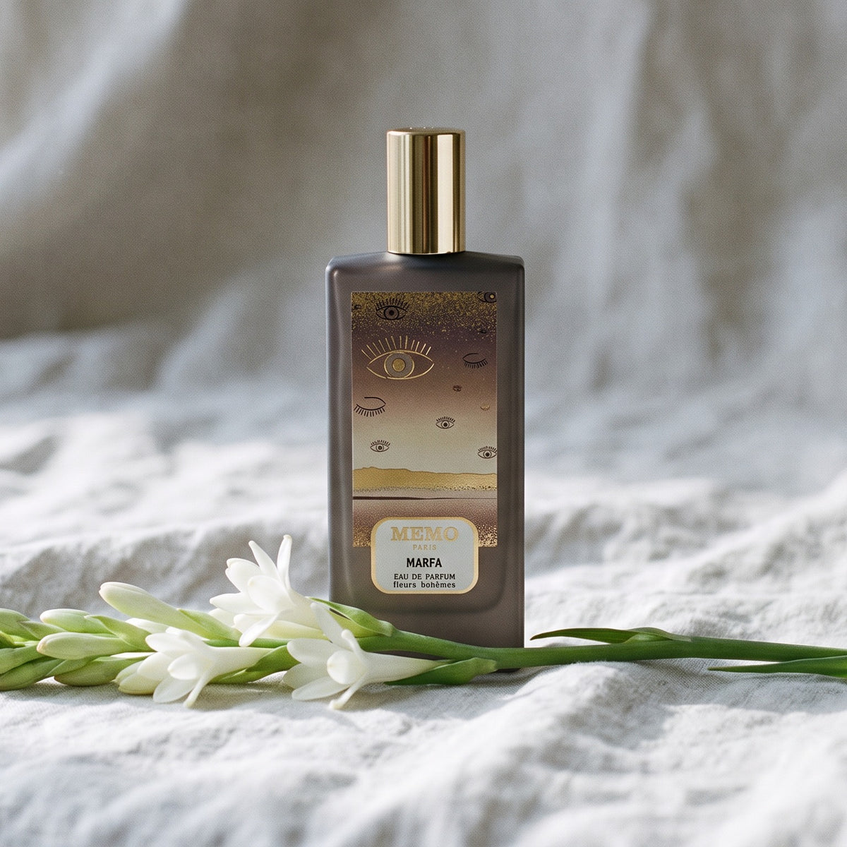 Memo Paris Marfa EDP on bleached linen with a single tuberose stem laid flat