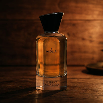 Miglia Fabbrica della Musa EDP on walnut side table with a pair of lit votives beside the bottle
