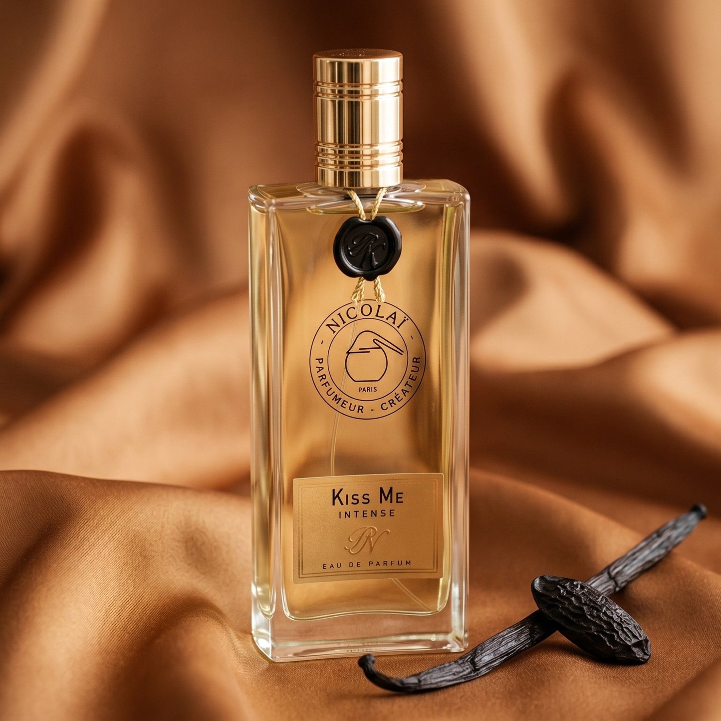 Nicolai Kiss Me Intense EDP on honey-colored satin with a stick of cinnamon and vanilla pods