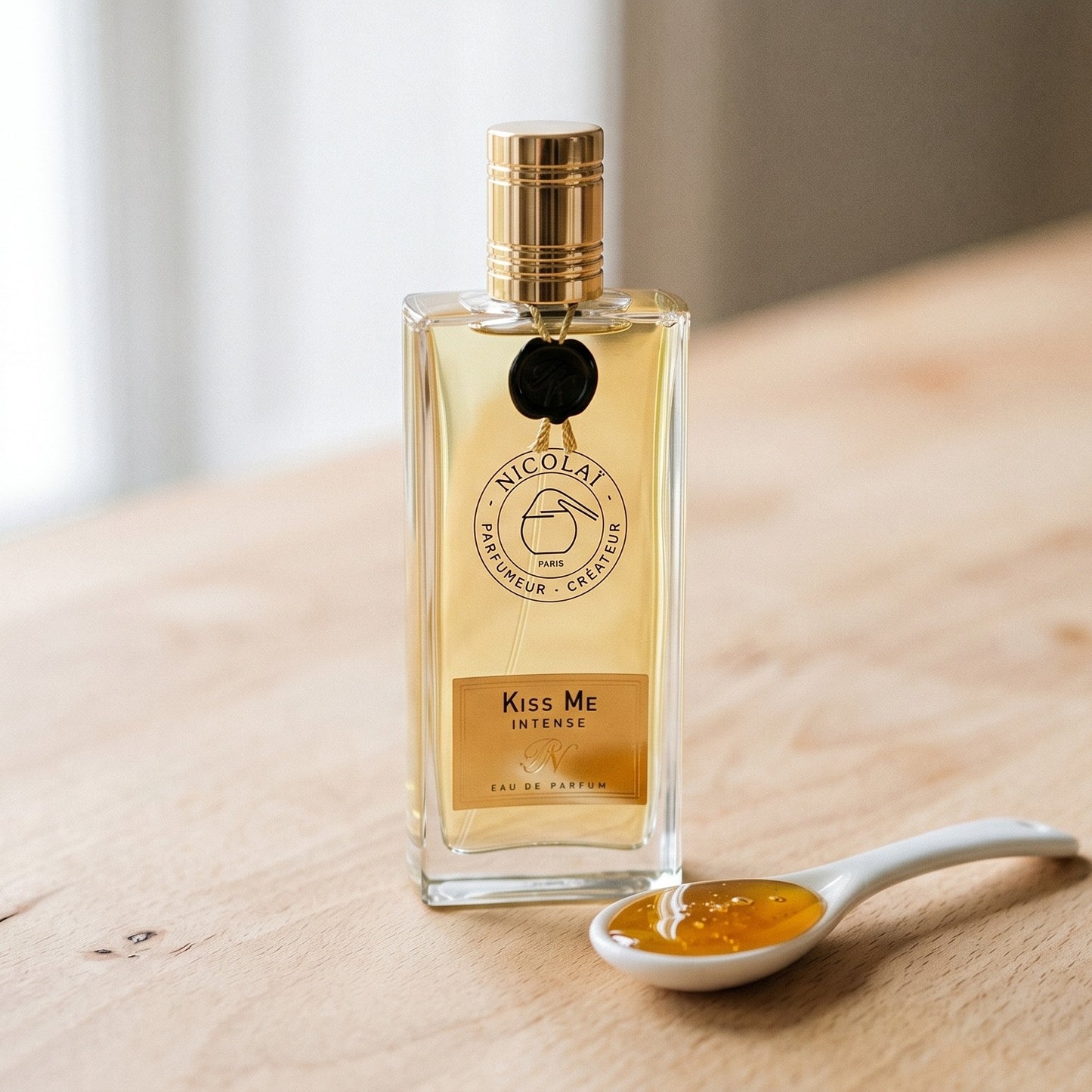 Nicolai Kiss Me Intense EDP on ivory-stained wood with a small bowl of crystallized ginger