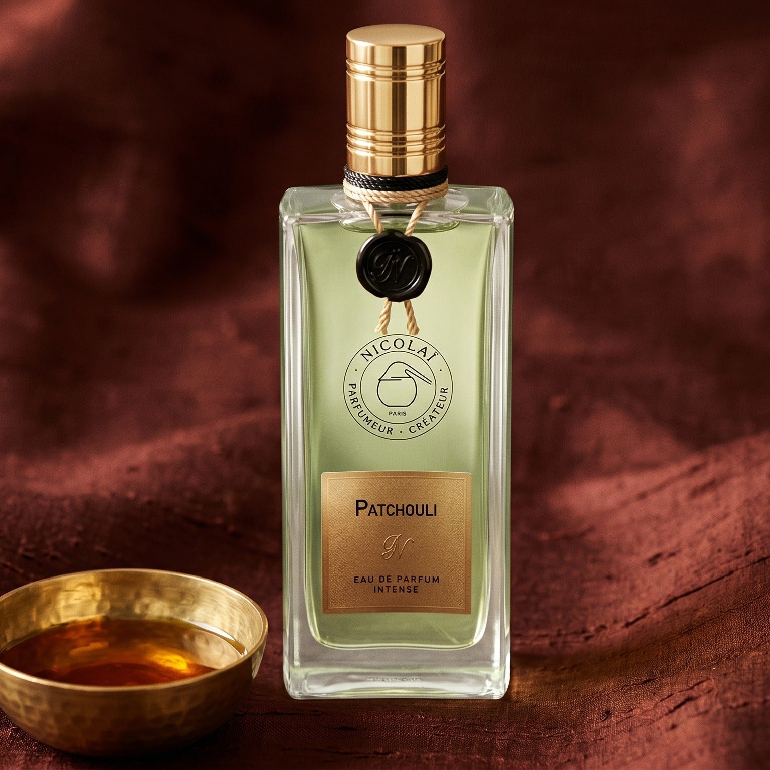 Nicolai Patchouli Intense EDP on raw silk of oxblood color with a brass bowl of ambergris tincture